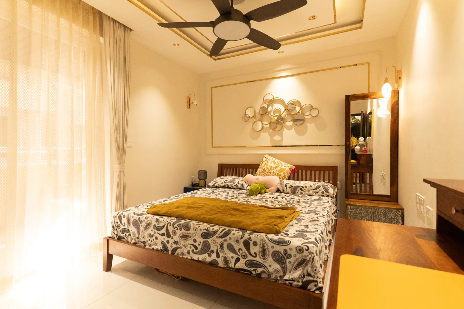 Bedroom with gold disc wall art and wooden bed — Divyarjuna